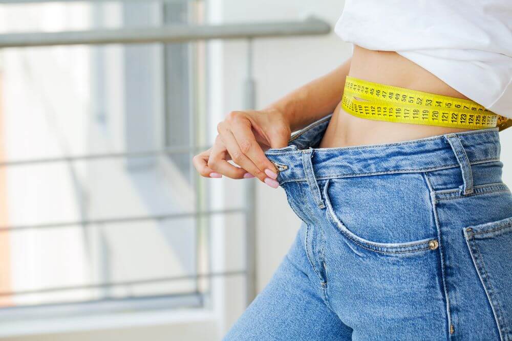 A woman measuring her waist.